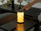 Gingko Design – Twist Hexagon Leuchte - Treibholz Walnuss - Mini, faltbare Tischleuchte aus Papier eingeschaltet auf einem Holztisch platziert