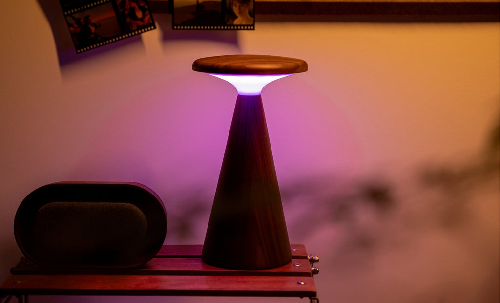 Gingko Design – Sylva Tischleuchte - Walnuss - 2 Größen, Tischleuchte aus Holz mit violettem Licht, auf einem Holztisch platziert