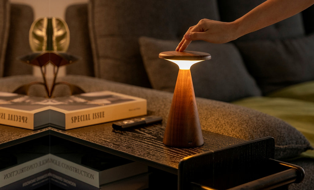 Gingko Design – Sylva Tischleuchte – Walnuss – 2 Größen, eingeschaltete Holztischleuchte auf einem Couchtisch