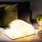Gingko Design – Lampa Smart Book LED - Len Miejski Szary - 2 Rozmiary, lampa książkowa otwarta i włączona na stoliku nocnym, przytulny klimat