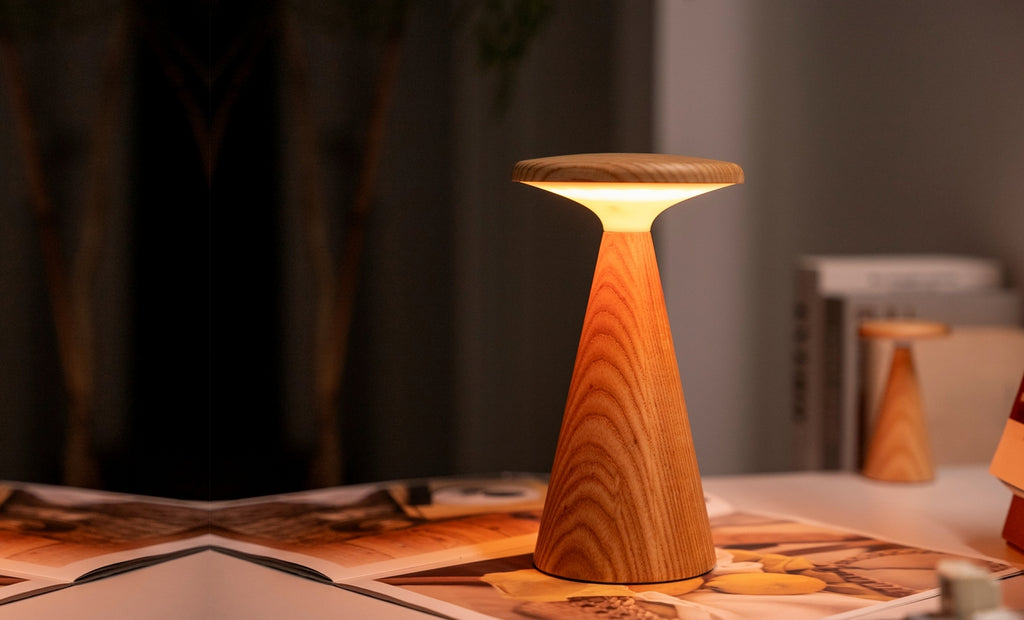 Gingko Design – Sylva Tischleuchte - Weiße Esche - 2 Größen, eingeschaltete Tischleuchte aus hellem Holz in einem gemütlichen Interieur