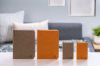 Gingko Design – Lámpara Smart Book LED - Lino Marrón Café - Mini, cuatro cuadernos de notas de diferentes tamaños y colores sobre una mesa