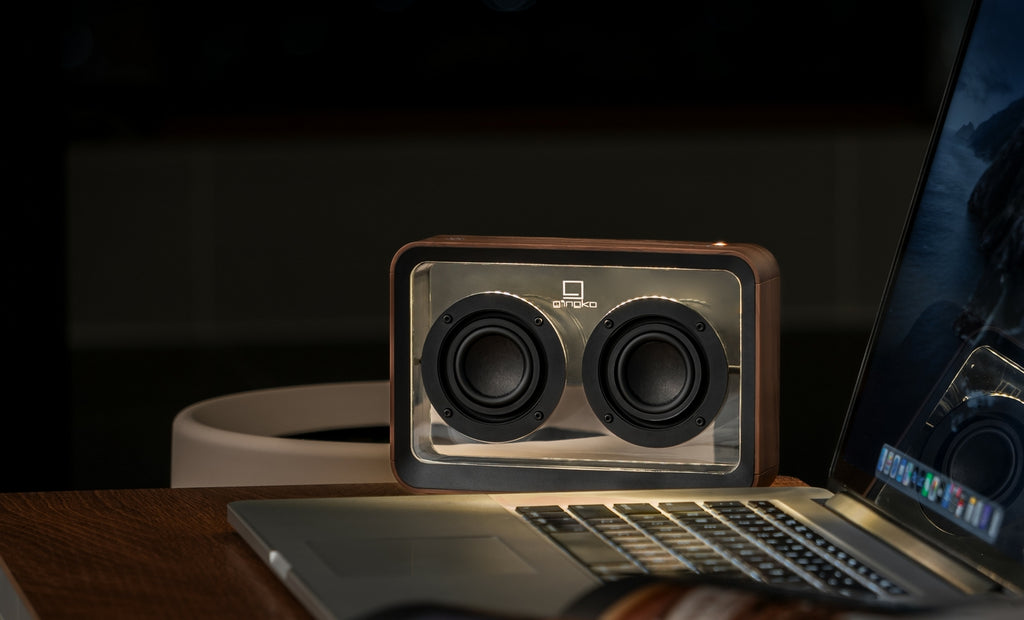 Gingko Design – Przezroczysty głośnik Bluetooth Mage – Orzech, przenośny głośnik z drewna i szkła postawiony na laptopie