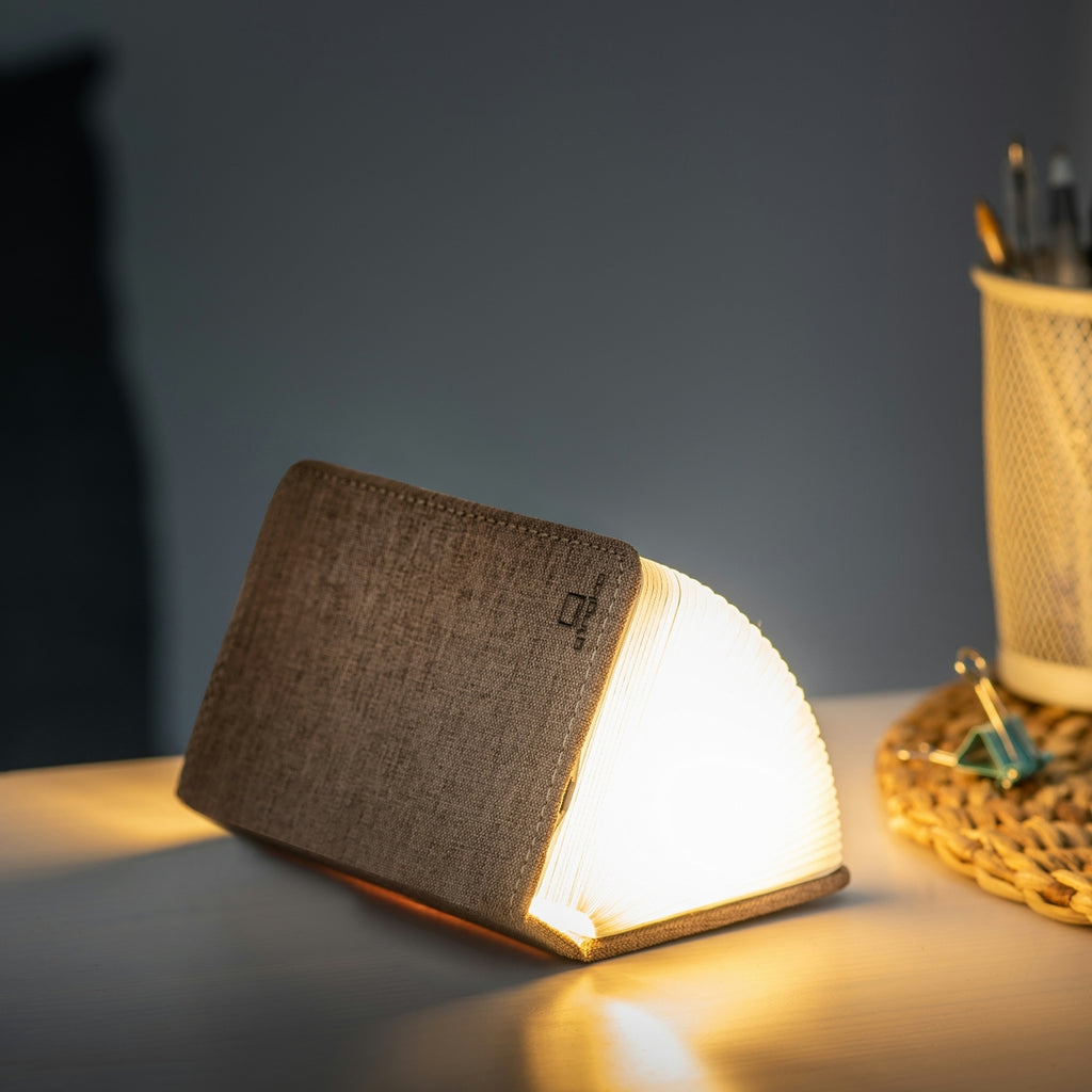 Gingko Design – Lámpara Smart Book LED - Lino Marrón Café - Mini, lámpara de noche en forma de libro abierto, colocada sobre un escritorio