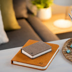 Gingko Design – Lámpara Smart Book LED - Lino Marrón Café - Mini, dos cuadernos de notas colocados sobre una mesa de centro en un salón