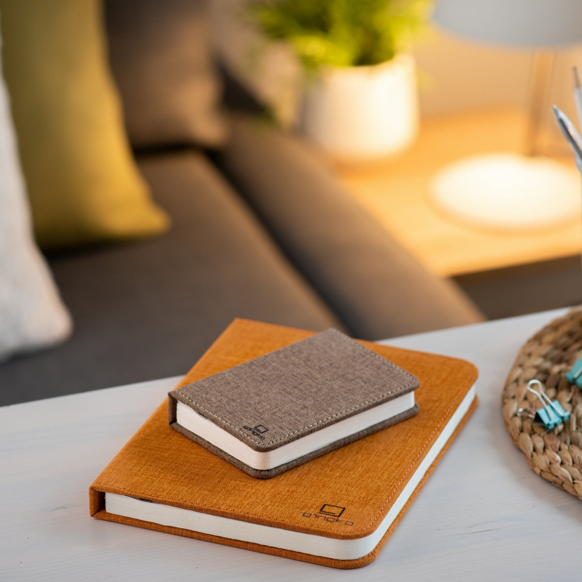 Gingko Design – Lámpara Smart Book LED - Lino Marrón Café - Mini, dos cuadernos de notas colocados sobre una mesa de centro en un salón
