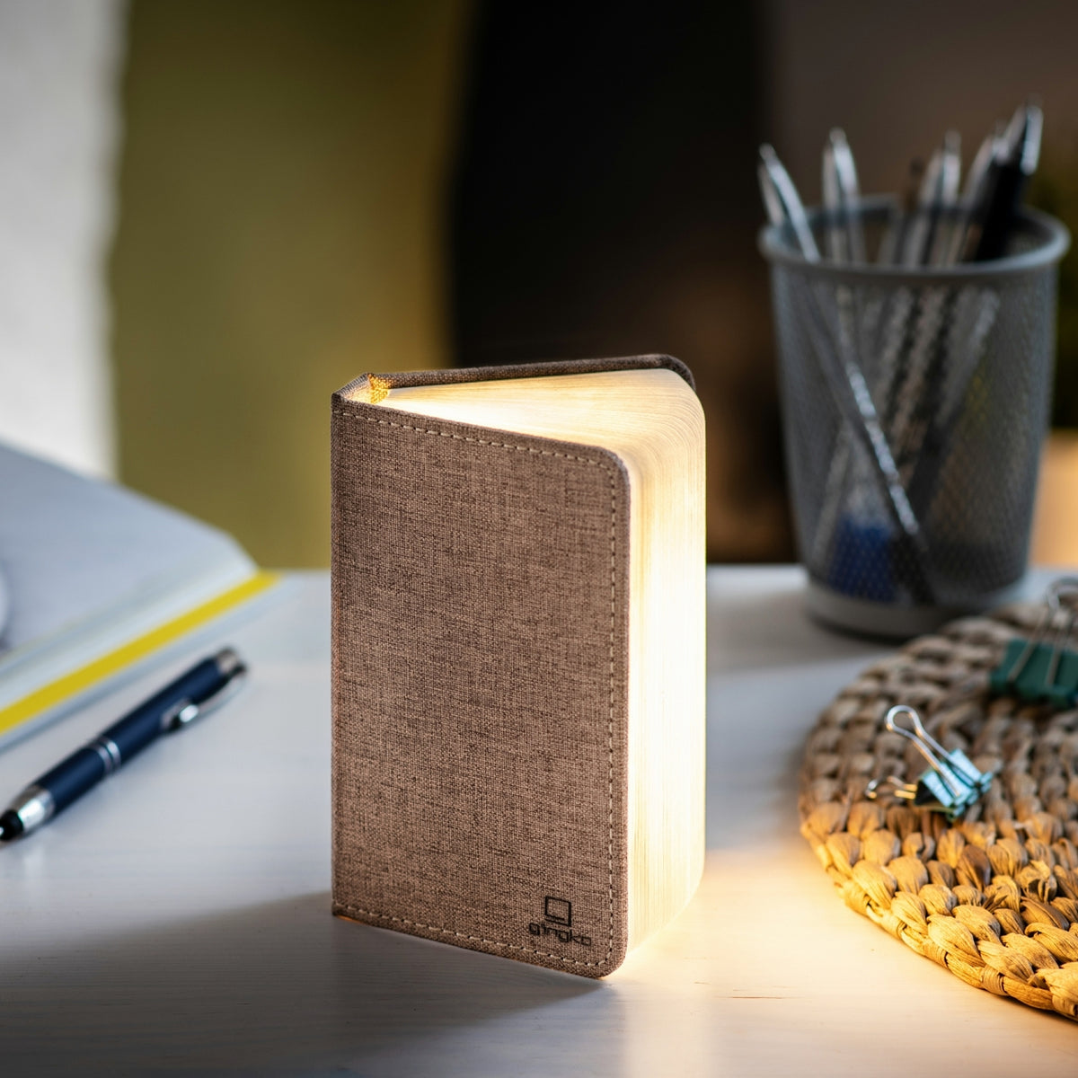 Gingko Design – Lámpara Smart Book LED - Lino Marrón Café - Mini, lámpara de noche en forma de libro abierto, colocada sobre un escritorio