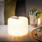 Gingko Design – Lámpara Smart Book LED - Lino Marrón Café - Mini, lámpara libro abierta luminosa colocada sobre un escritorio de madera