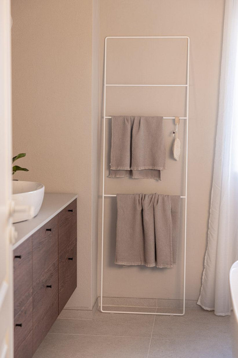 Helles Badezimmer mit Handtuchleiter Estina, auf der dos handtücher hängen.