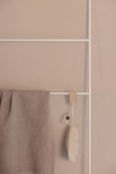 Handtuchleiter ESTINA mit einem beige Handtuch und einem natural Reinigungsschwamm an einer white Wand.