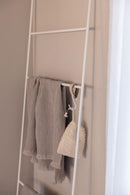 Handtuchleiter mit weichen, grauen Handtüchern und einer dekorativen gespannten Tasche an der Wand.