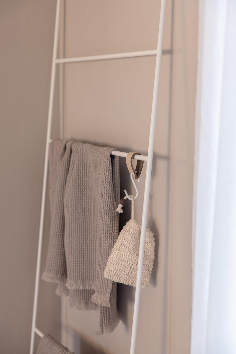 Handtuchleiter mit weichen, grauen Handtüchern und einer dekorativen gespannten Tasche an der Wand.