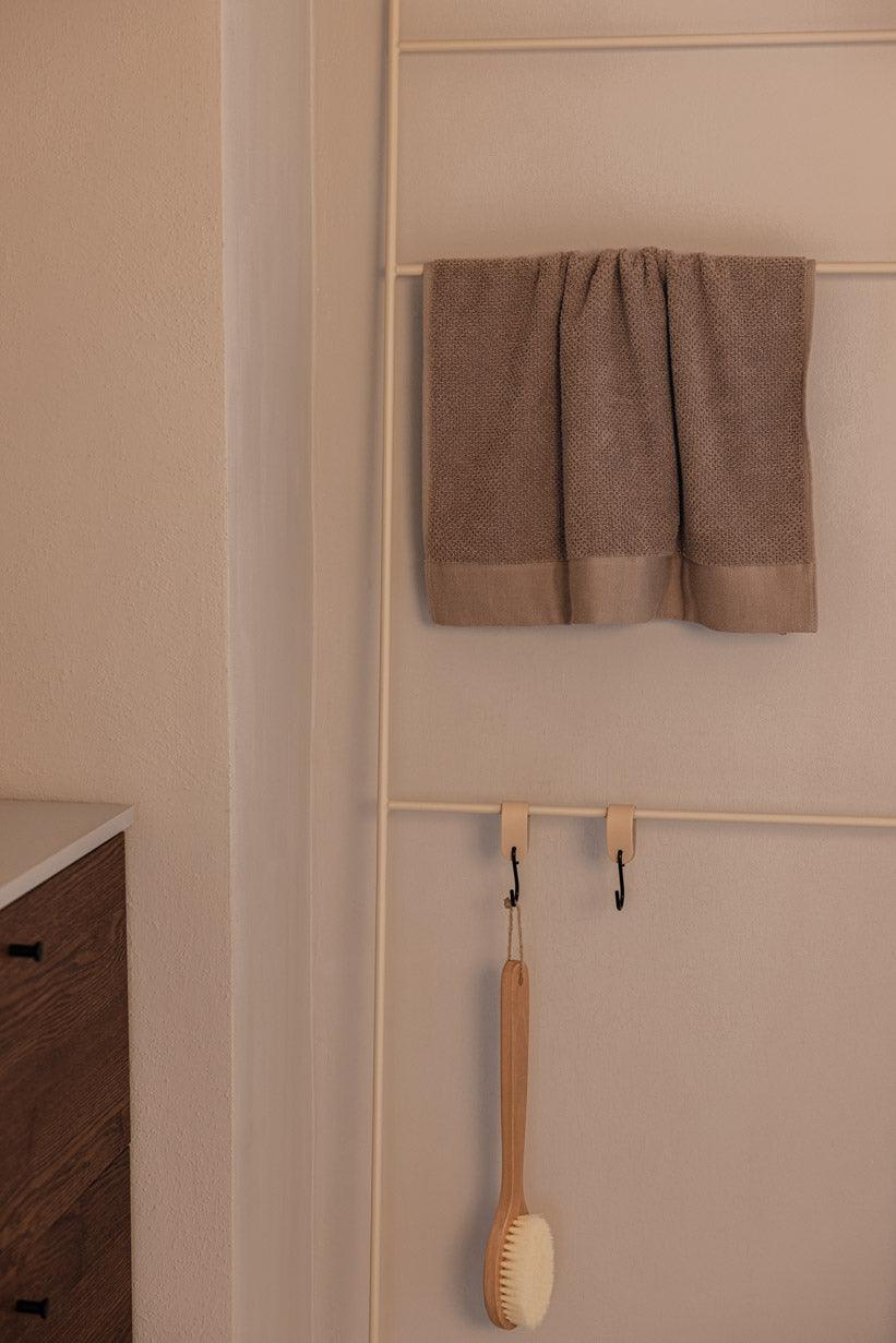 Handtuchleiter mit einem handtuch und einer Bürste, ideal für Badezimmeraccessoires.