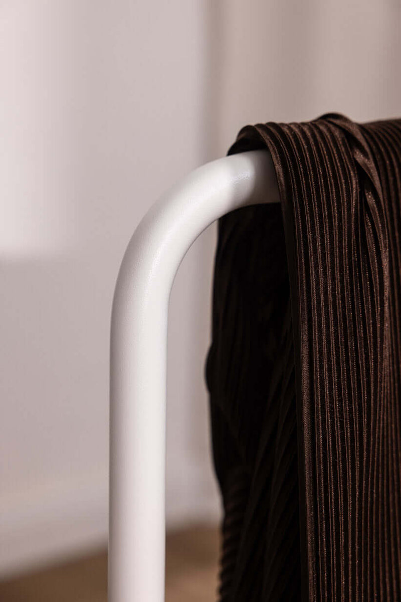 Der Herrendiener zeigt eine Nahaufnahme eines minimalistischen Kleiderständers mit einem braunen Kleidungsstück.