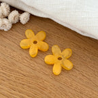 Instants Plaisirs – Fleurs "Maria" Acétate, deux breloques en forme de fleur jaune sur une table en bois