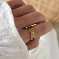 Instants Plaisirs – Bague Aya - Acier, bague dorée à motif tressé portée sur un doigt, vue de face