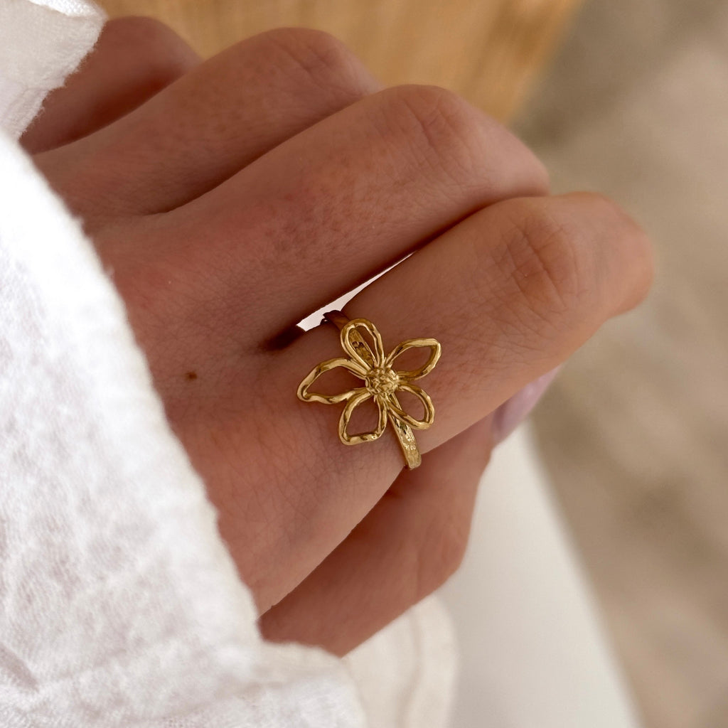 Instants Plaisirs – Bague Eline - Acier, bague dorée en forme de fleur portée sur un doigt, vue de côté