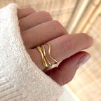 Instants Plaisirs – Bague "Mila" Acier, bague dorée portée sur un doigt, avec un pull en maille crème