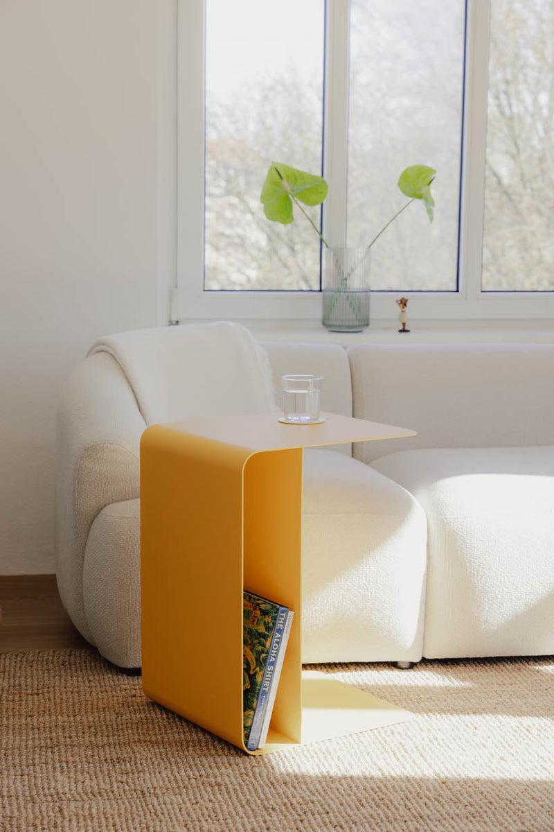 Beistelltisch COSMO en diseño moderno con bebidas fläche neben einem Sofa platziert, ideal für Getränke und Bücher.