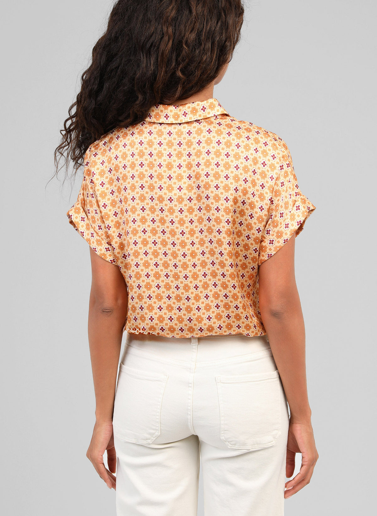 An'ge – Chemise Kacilia Domini Ble, femme de dos portant un chemisier court à motifs et un pantalon clair