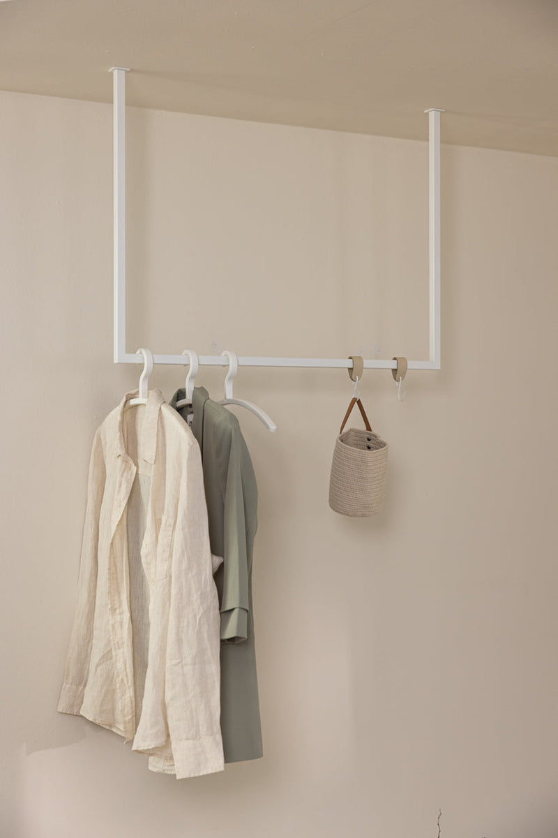 Kleiderstange RUBI mit mehreren Kleiderbügeln, die elegante und schlichte Modeartikel halten.