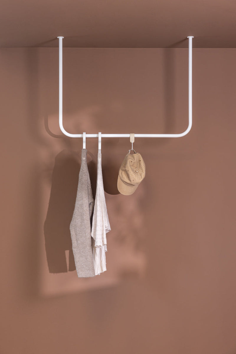 Kleiderstange ENIO an einer Wand montiert mit Kleidern und einer Mütze, Minimalistisches Design, Platzersparnis.