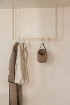 Kleiderstange RUBI mit Kleidungsstücken und einer Tasche an der Wand, minimalist Design für Ankleidebereiche.