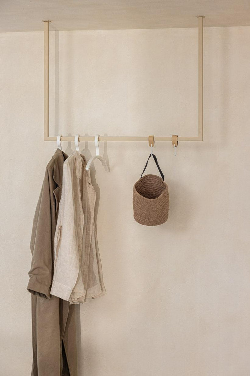 Kleiderstange RUBI mit Kleidungsstücken und einer Tasche an der Wand, minimalistisches Design für Ankleidebereiche.