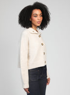 An'ge – Gilet Lakeyla Ecru, mannequin femme de profil portant un cardigan en maille crème et un jean