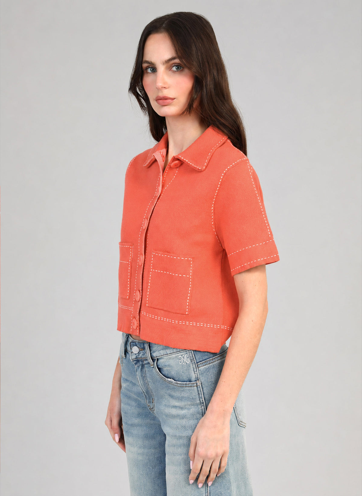 An'ge – Gilet Lebilly Piment, mannequin portant une chemise courte orange avec surpiqûres blanches, vue de profil