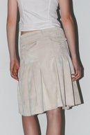 Vista frontal de tres cuartos: falda con volantes en color beige claro, con movimiento fluido y silueta femenina.