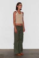 Vista frontal de tres cuartos: top en tonos neutros combinado con pantalones verdes, aspecto minimalista y elegante.