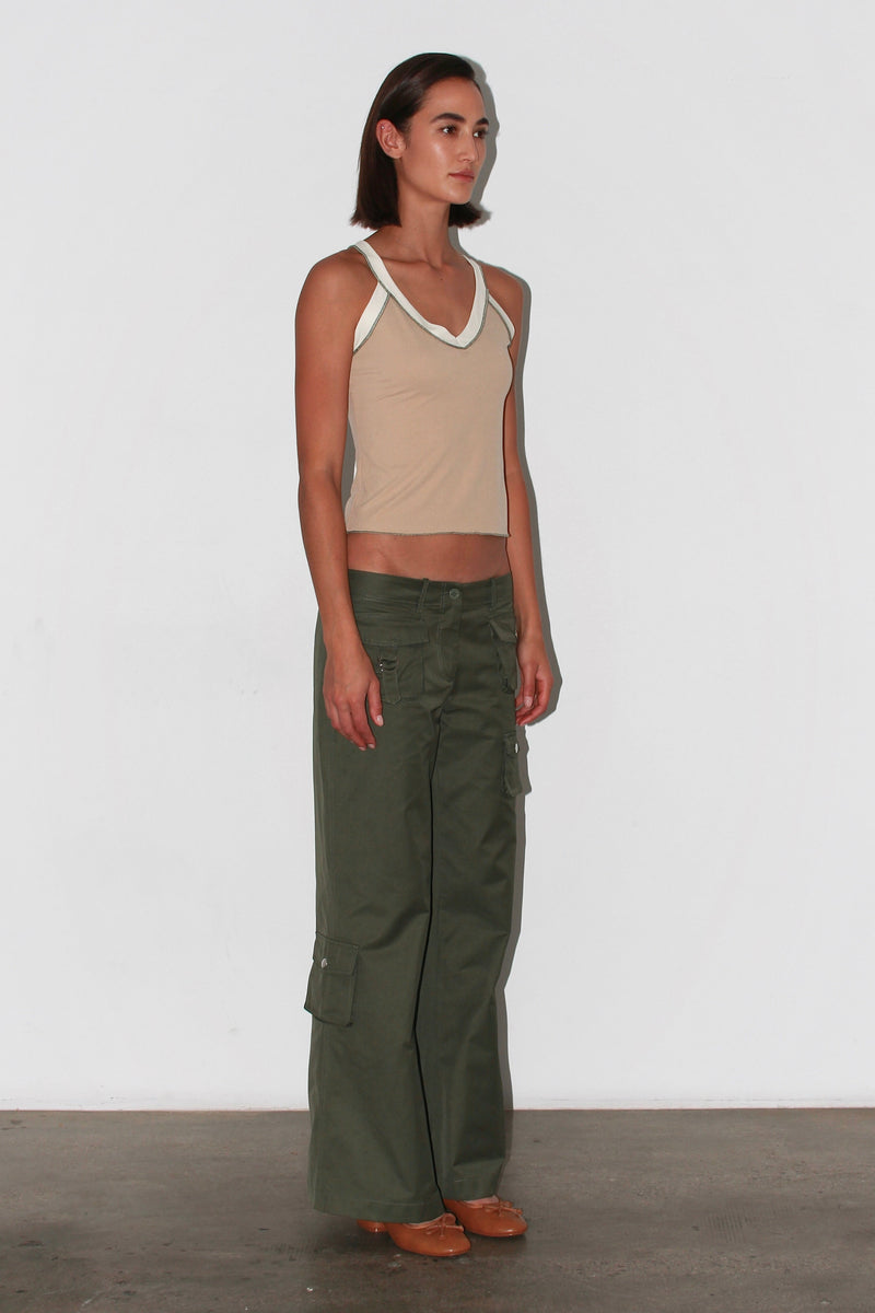 Vista frontal de tres cuartos: top en tonos neutros combinado con pantalones verdes, aspecto minimalista y elegante.