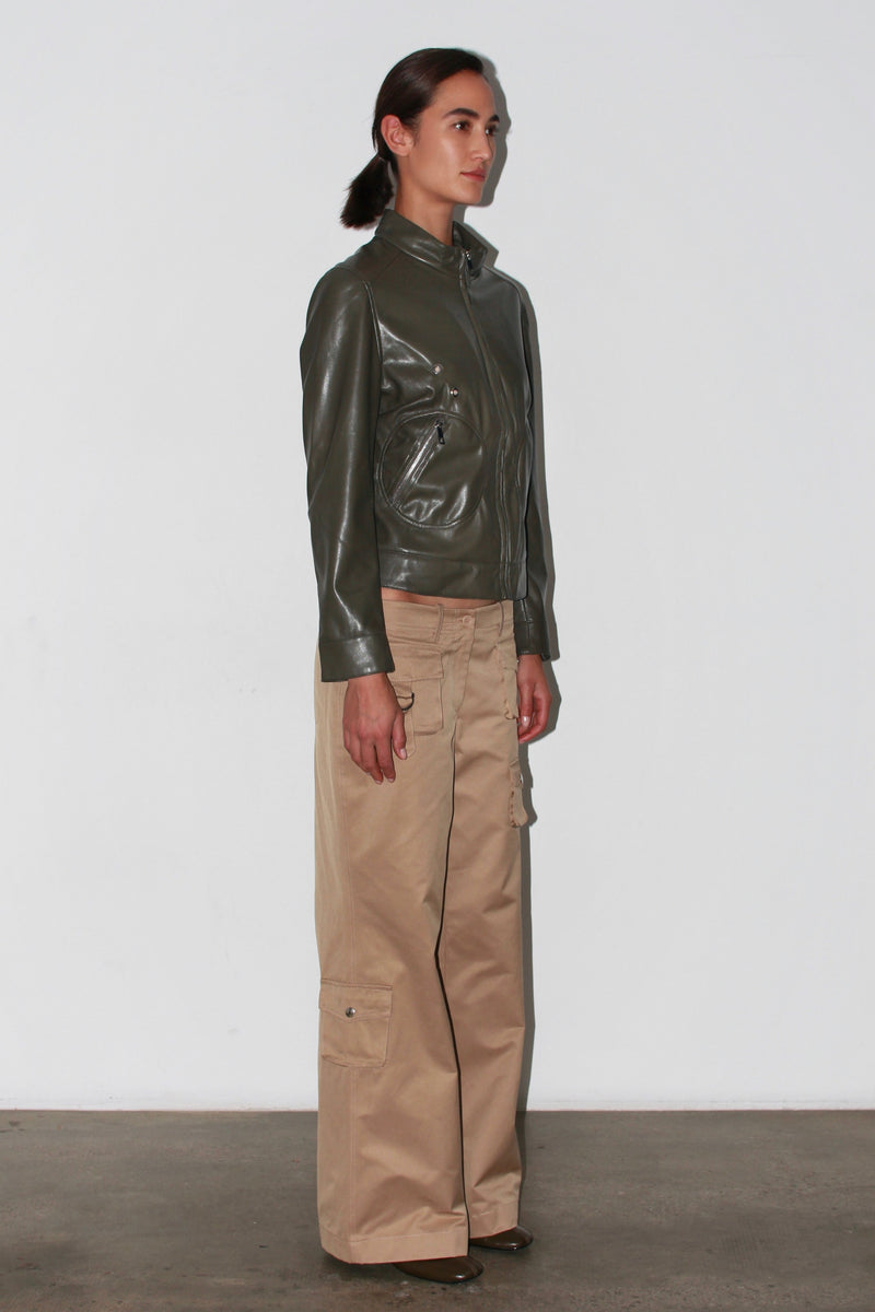 Vista frontal de tres cuartos: chaqueta de cuero entallada abierta sobre un top beige, aspecto elegante y versátil.