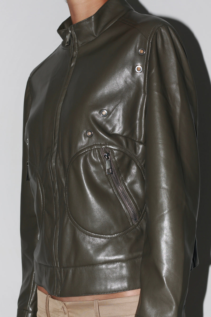 Primer plano lateral: chaqueta de cuero verde oscuro con costuras detalladas y acabado brillante.