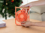 Gingko Design – Tragbarer Ventilator Lyra - Pfirsich, oranger Tischventilator mit Holzfuß, auf einem Holztisch stehend