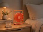 Gingko Design – Tragbarer Ventilator Lyra - Pfirsich, oranger Ventilator auf einem Holznachttisch
