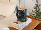 Gingko Design – Ventilador Portátil Lyra - Gris Espacial, ventilador negro colocado sobre libros en una mesa de madera