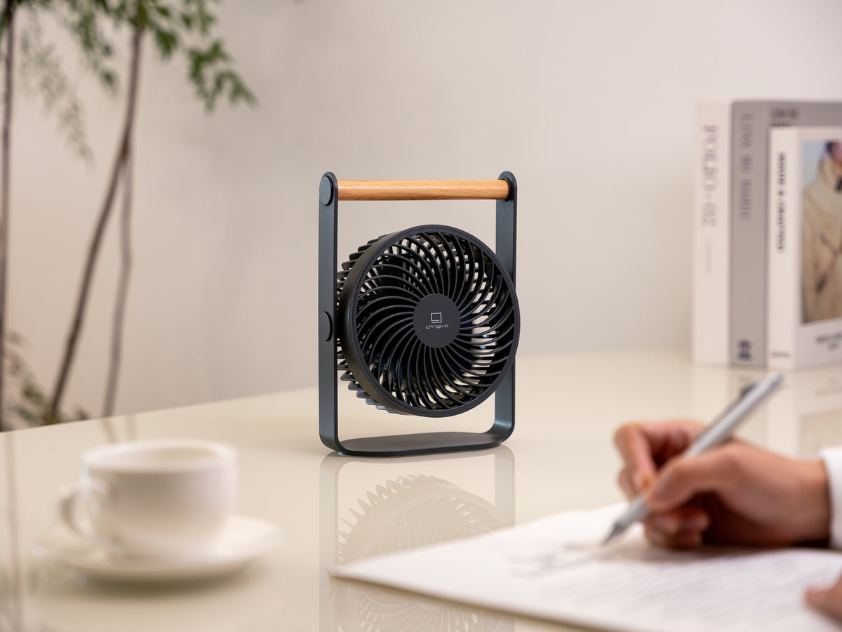 Gingko Design – Ventilador Portátil Lyra - Gris Espacial, ventilador de mesa negro y madera, colocado sobre un escritorio