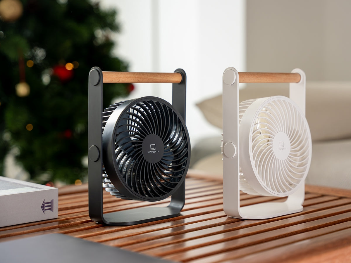 Gingko Design – Ventilador Portátil Lyra - Gris Espacial, dos ventiladores de mesa, negro y blanco, sobre una mesa de madera