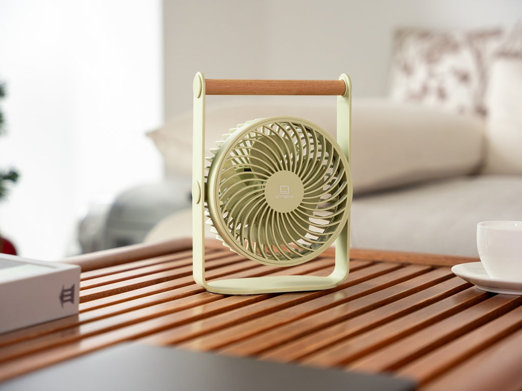 Gingko Design – Ventilador Portátil Lyra - Gris Espacial, ventilador de mesa verde claro con asa de madera sobre una mesa de centro
