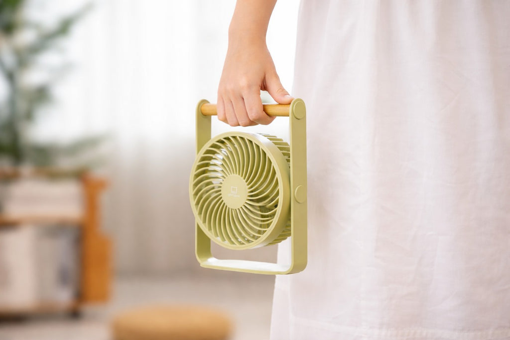 Gingko Design – Draagbare ventilator Lyra - Olijfgroen, lichtgroene draagbare ventilator met houten handvat, vastgehouden door iemand