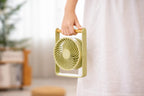 Gingko Design – Draagbare ventilator Lyra - Olijfgroen, lichtgroene draagbare ventilator met houten handvat, vastgehouden door iemand