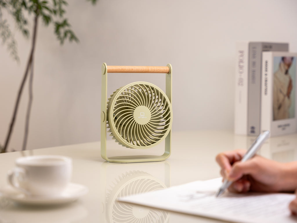 Gingko Design – Draagbare ventilator Lyra - Olijfgroen, lichtgroene tafelventilator met houten handvat op een bureau