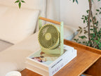 Gingko Design – Draagbare ventilator Lyra - Olijfgroen, groene ventilator op boeken op een houten tafel