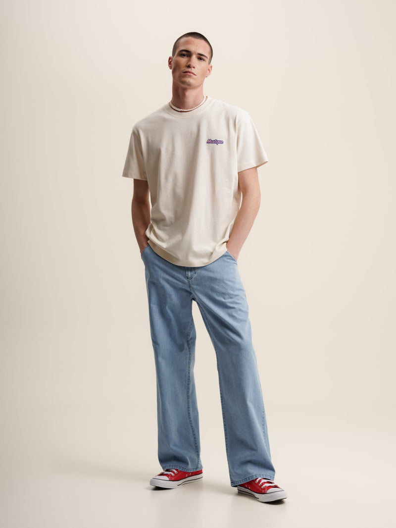  A man donning a fruit market-themed ecru t-shirt, displaying a cartoon image of a man and a woman.