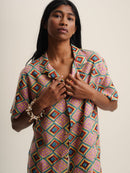 The model wears an IBIZA SHIRT with a vibrant geometric print, adding a pop of color to their outfit.