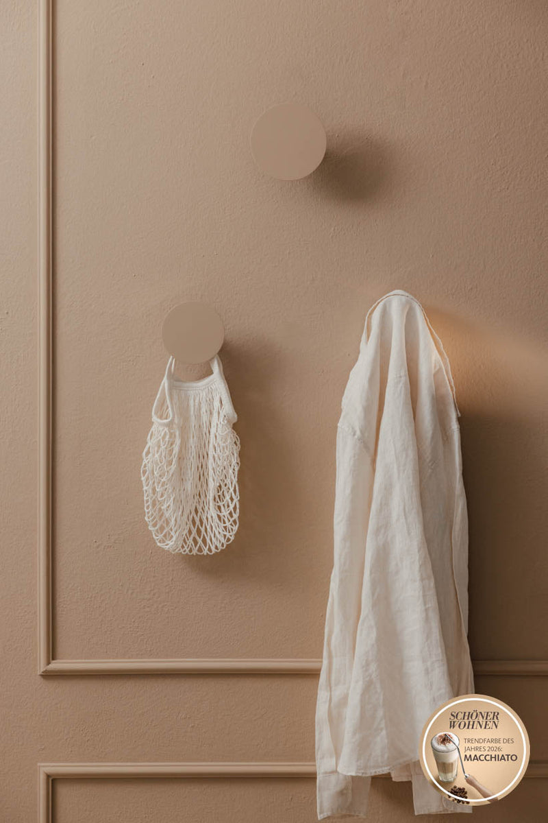 Wandhaken LOU mit Kleidungsstück und Netztasche an wandmontierter Oberfläche in minimalistischem Design.