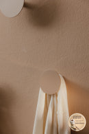 WANDHAKEN LOU in minimalist design mit einem hellen Tuch an der Wand befestigt