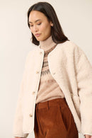 Col à revers structuré, doublure ton sur ton visible sur l’envers du col, manches longues et de couleur écru.